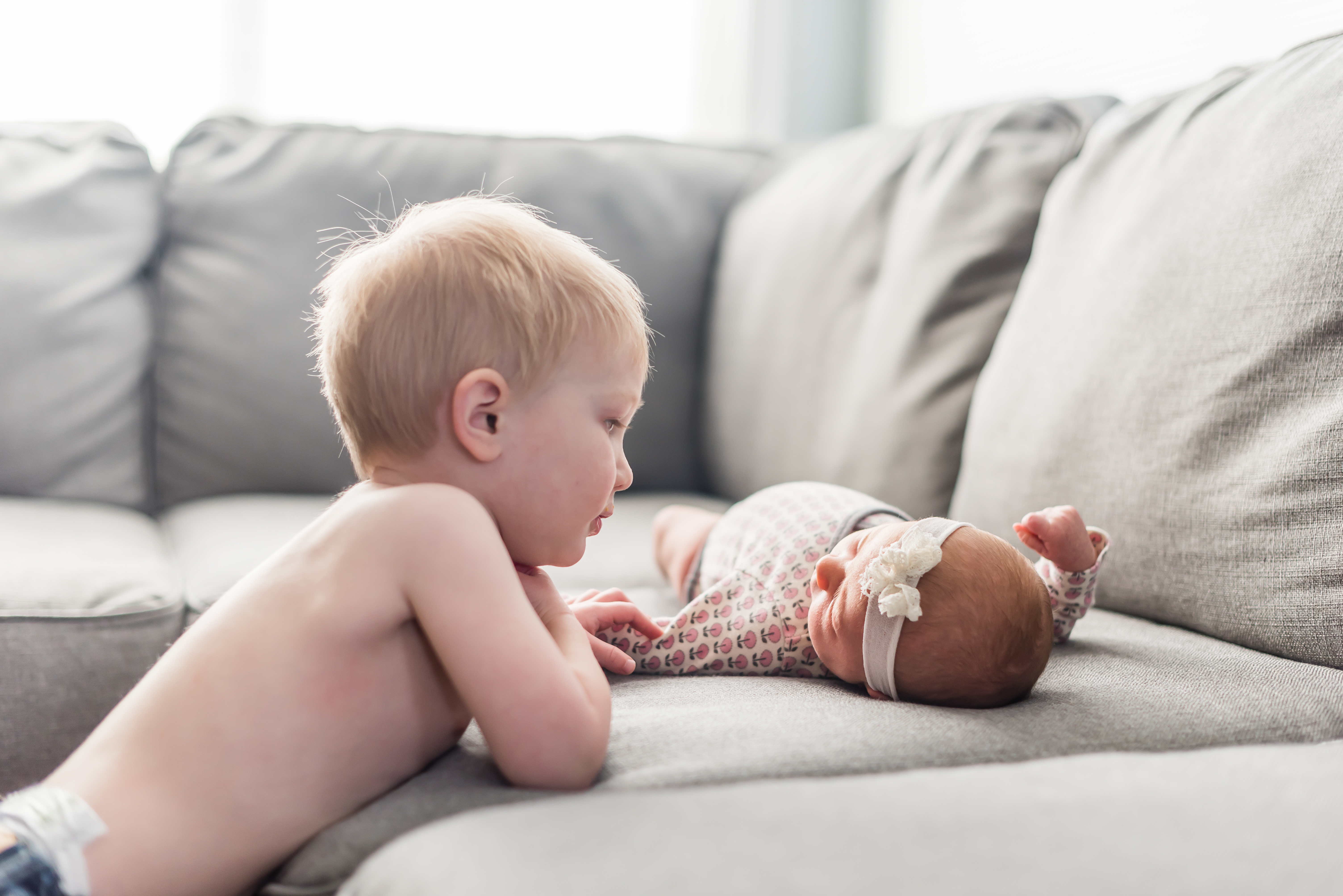 big brother looking at new baby sister at home