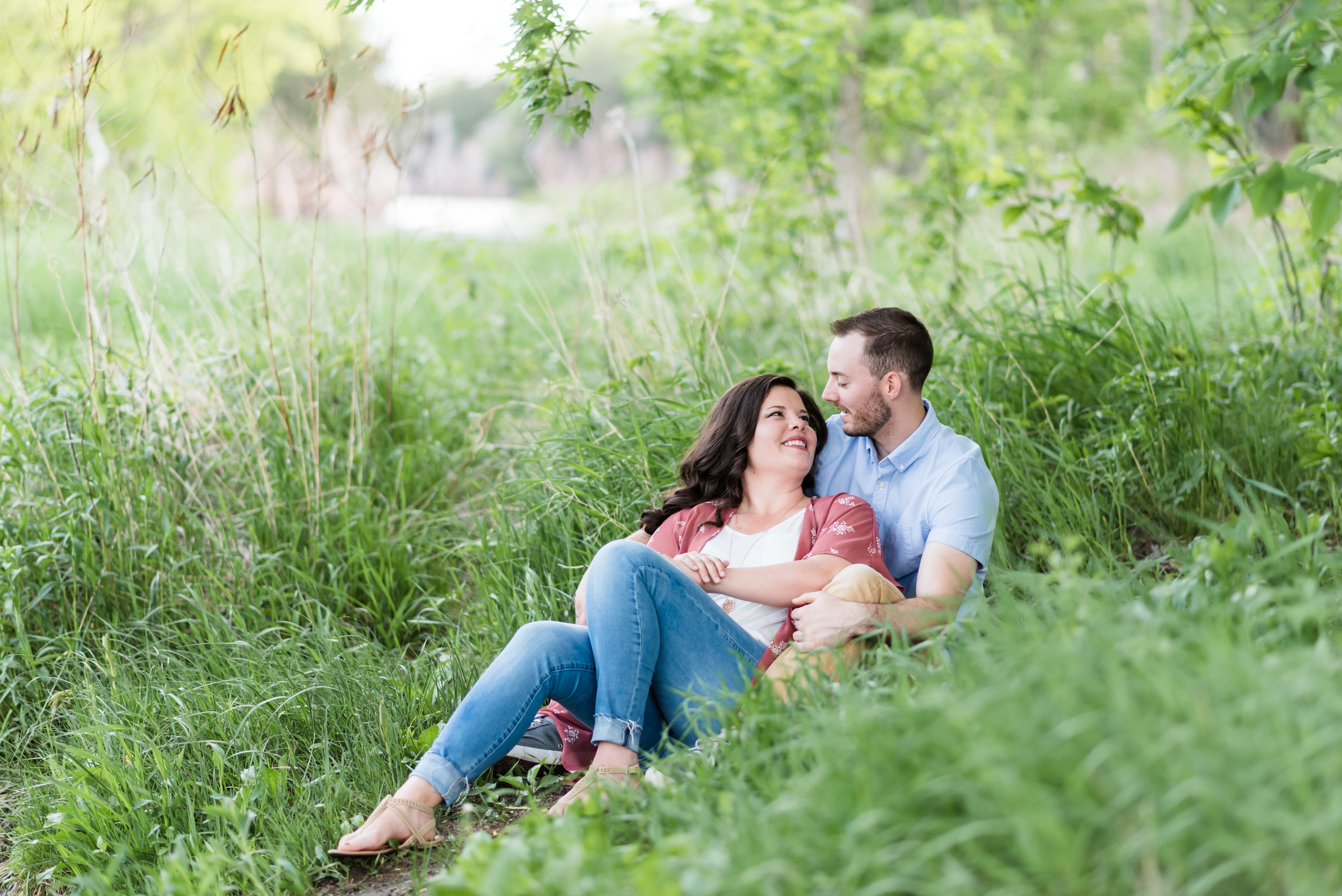 engaged couple laying in grass looking at each other