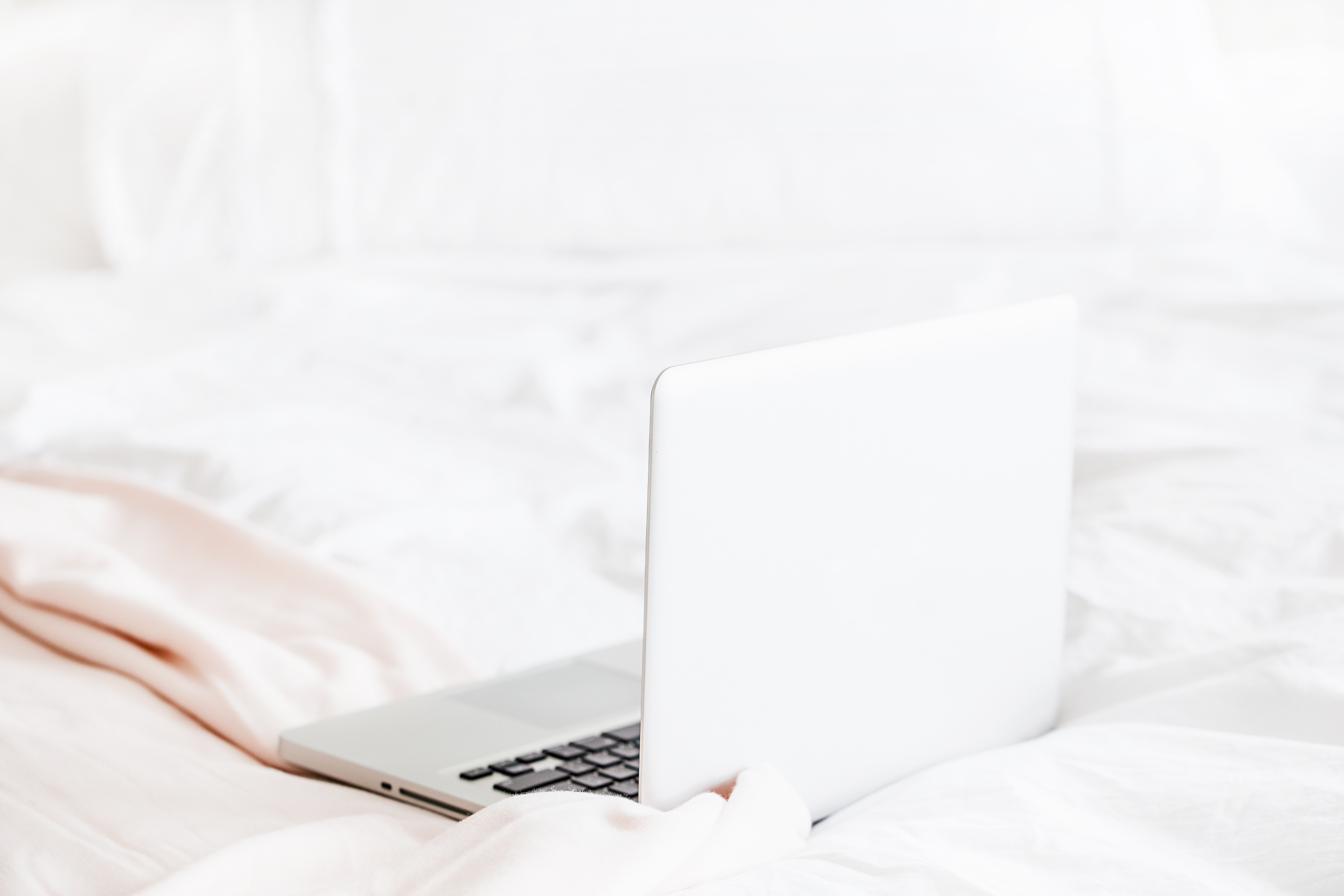 laptop on white bed
