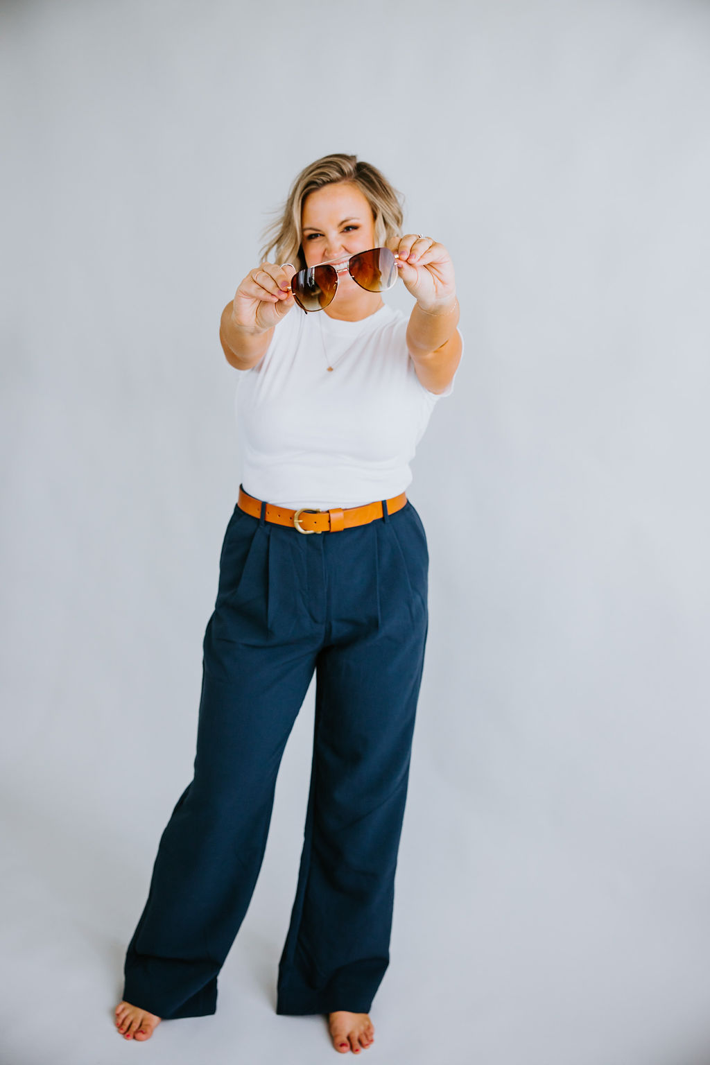Maddie, brand photographer, posing with a pair of sunglasses