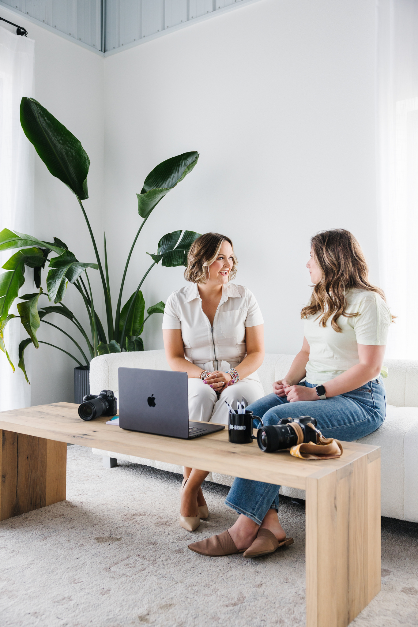 Maddie, brand photographer, talking to a client in front of her laptop and camera during a brand photography shoot