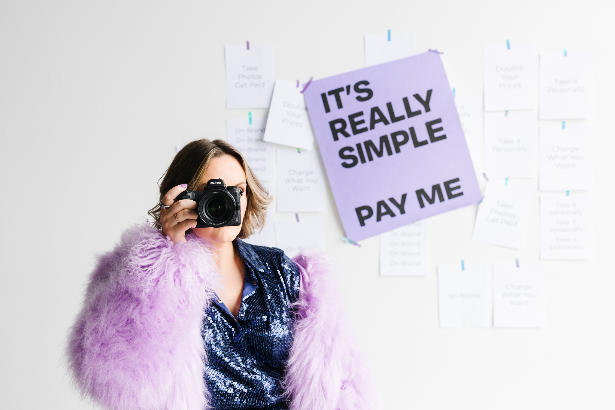 Maddie Peschong photographer in studio with camera and purple coat for personal brand shoot
